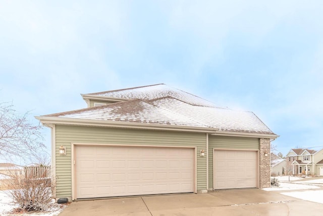 exterior space with a garage, brick siding, and roof with shingles