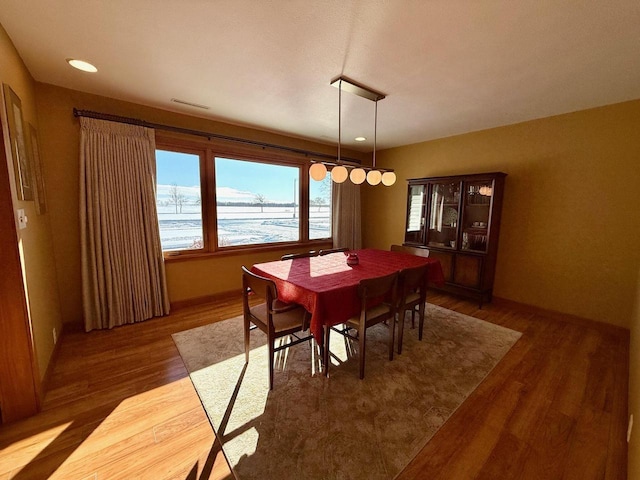 dining space featuring a water view, dark wood finished floors, visible vents, and recessed lighting