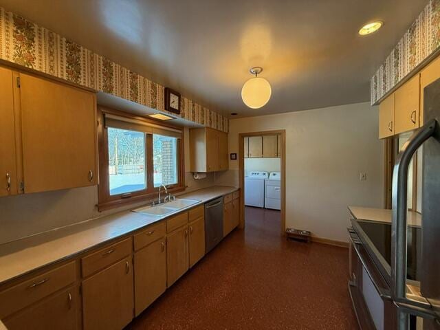 kitchen featuring light countertops, washing machine and dryer, a sink, dishwasher, and baseboards