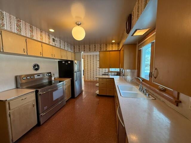 kitchen with a sink, visible vents, light countertops, appliances with stainless steel finishes, and wallpapered walls