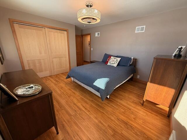 bedroom featuring light wood-style floors, visible vents, and a closet