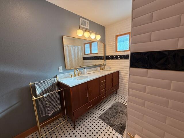 bathroom featuring double vanity, visible vents, and a sink