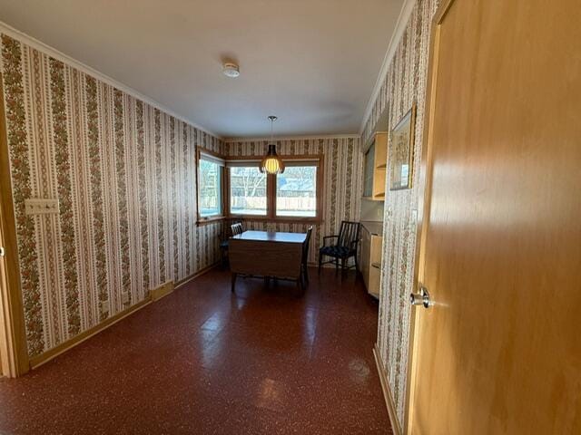 unfurnished dining area with baseboards, dark floors, ornamental molding, and wallpapered walls