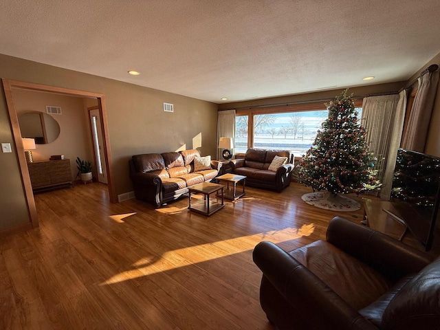 living room featuring a textured ceiling, visible vents, and wood finished floors