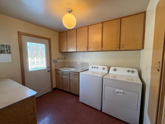 laundry area with cabinet space, dark floors, washer and clothes dryer, and a sink