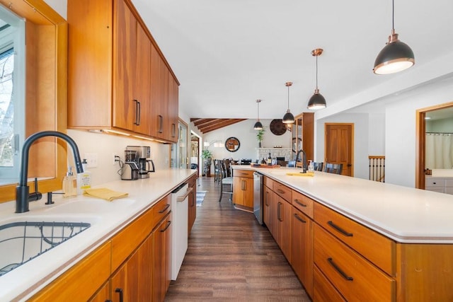 kitchen featuring light countertops, hanging light fixtures, stainless steel dishwasher, a kitchen island with sink, and a sink