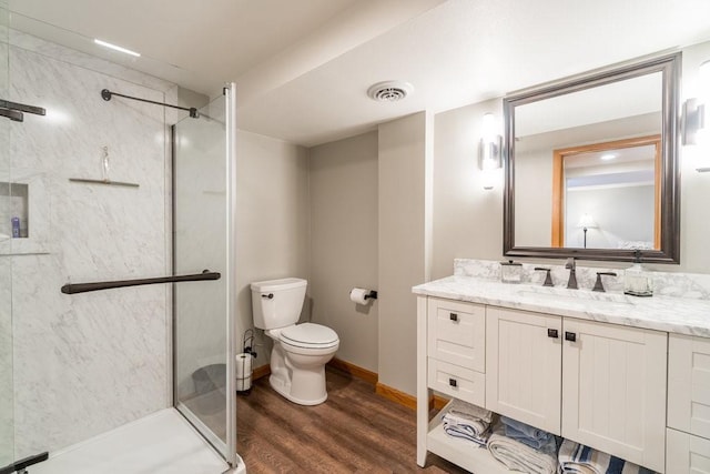 full bath featuring wood finished floors, vanity, baseboards, visible vents, and a shower stall