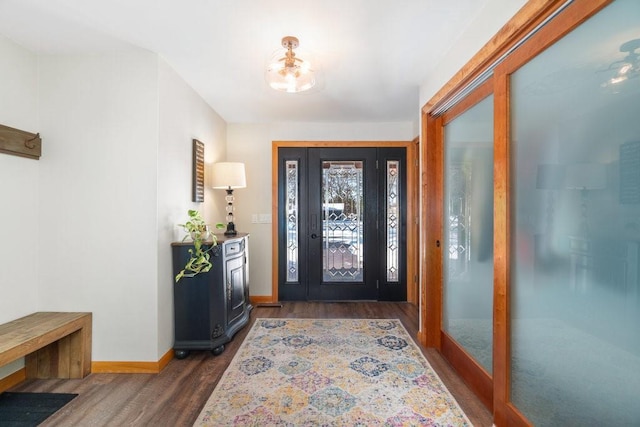 foyer entrance featuring a chandelier, dark wood finished floors, and baseboards