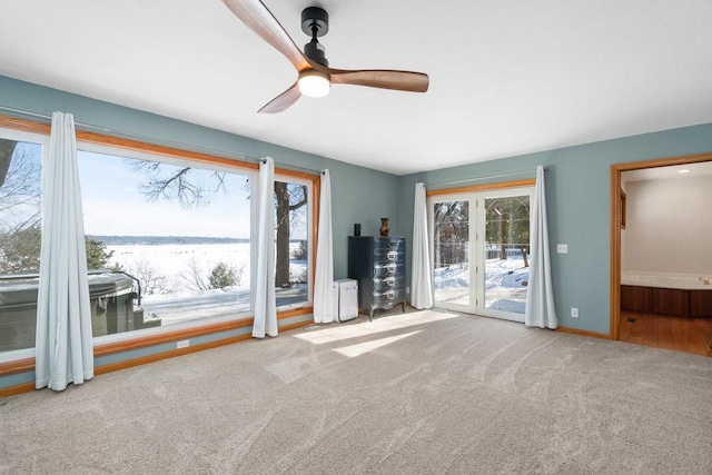 unfurnished living room featuring baseboards, a ceiling fan, and light colored carpet