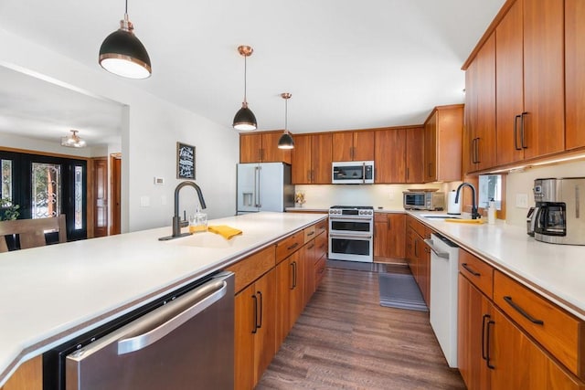 kitchen with a sink, stainless steel appliances, light countertops, and hanging light fixtures