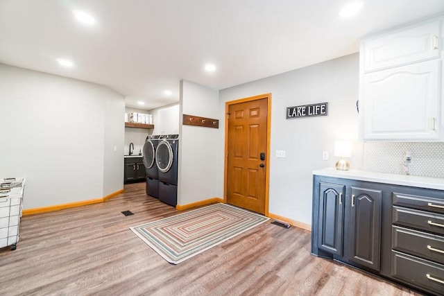 laundry area with baseboards, washer and clothes dryer, and light wood-style floors