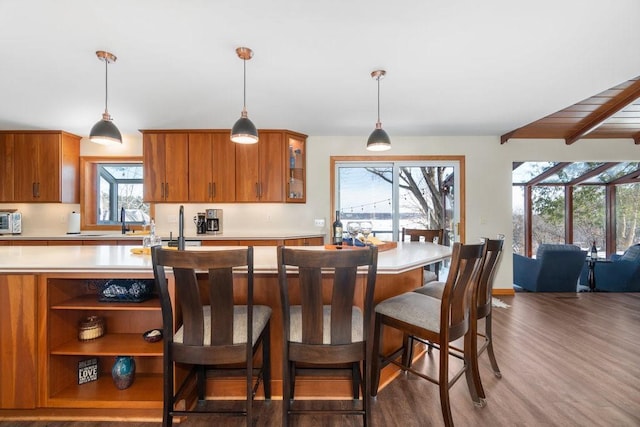 kitchen with light countertops, decorative light fixtures, glass insert cabinets, and brown cabinets