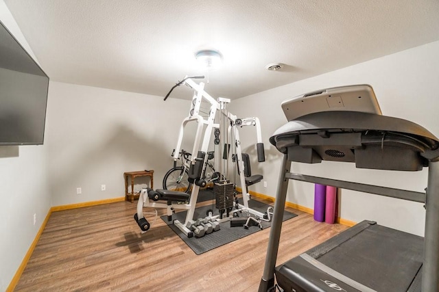 workout area featuring visible vents, baseboards, and wood finished floors