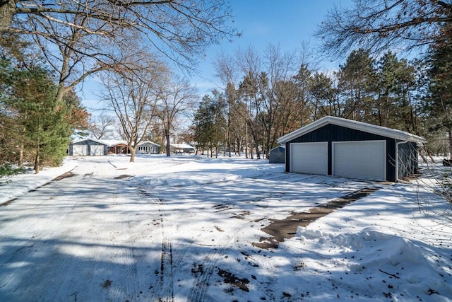 snowy yard with a detached garage and an outdoor structure