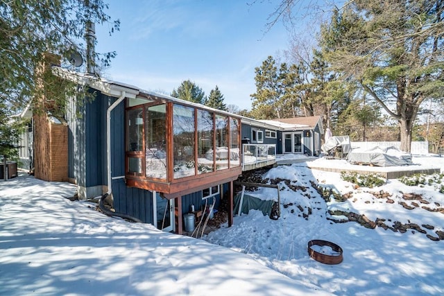 snow covered rear of property with a garage and a wooden deck