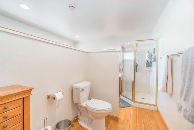 full bathroom featuring a stall shower, wood finished floors, toilet, and baseboards