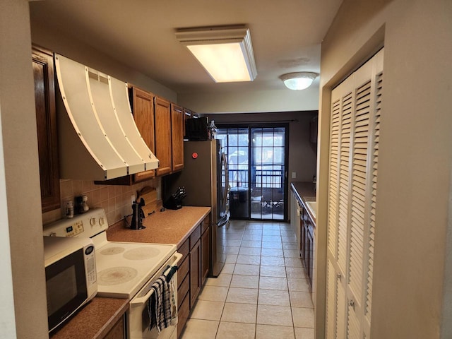 kitchen with decorative backsplash, brown cabinets, freestanding refrigerator, extractor fan, and white range with electric cooktop