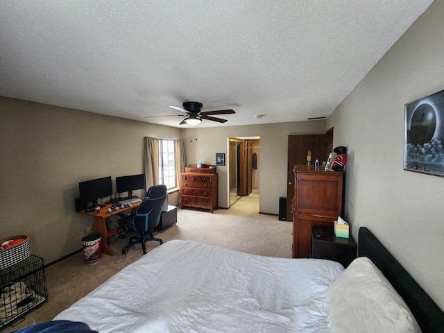 bedroom featuring light carpet, ceiling fan, a textured ceiling, and a spacious closet