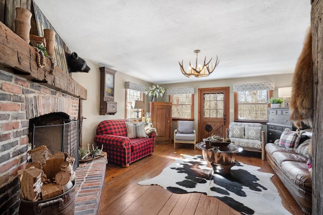 living room with a fireplace, an inviting chandelier, and wood finished floors