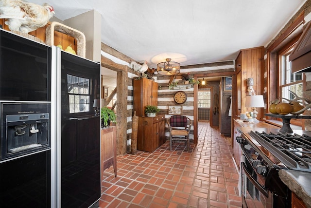 kitchen with brick floor, wood walls, a healthy amount of sunlight, black fridge, and gas stove