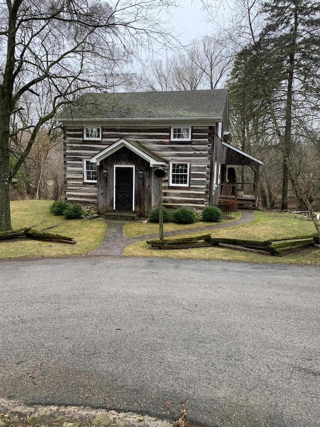 log cabin featuring a front yard, driveway, and log siding