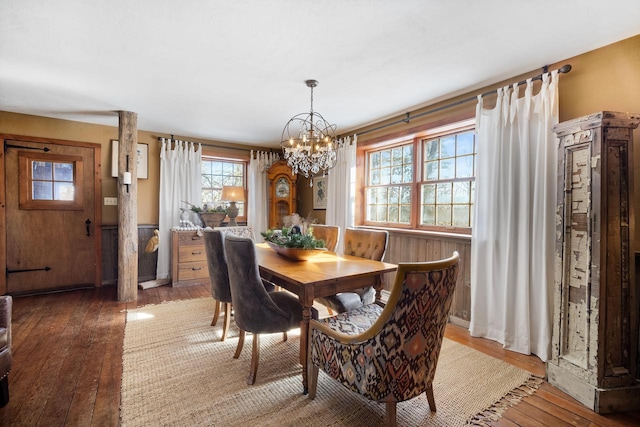 dining area featuring wooden walls, a chandelier, and wood finished floors