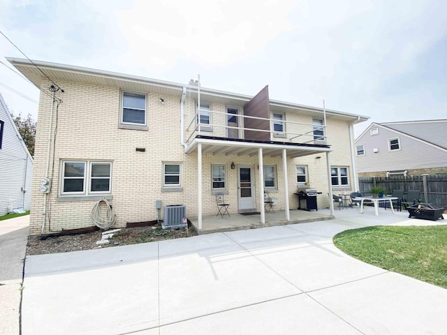 back of house with a patio, a balcony, fence, cooling unit, and brick siding