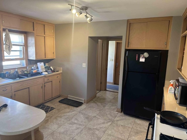 kitchen featuring freestanding refrigerator, light countertops, a sink, and baseboards