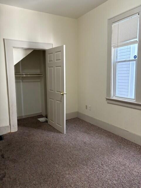 unfurnished bedroom with a closet, carpet flooring, and baseboards