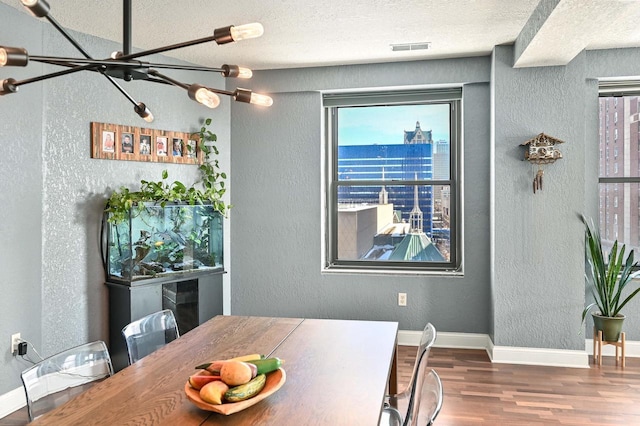 dining room with dark wood-style floors, visible vents, and a textured wall