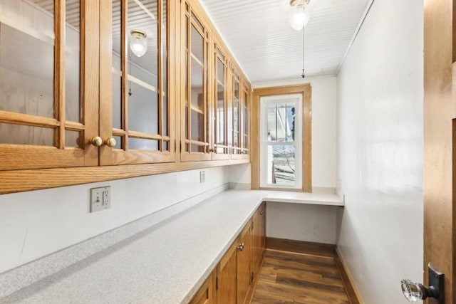 bar featuring baseboards, dark wood-type flooring, and built in study area