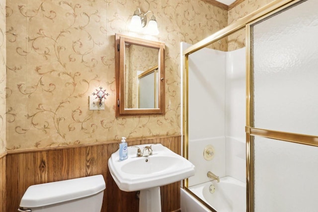 full bath featuring a wainscoted wall, toilet, enclosed tub / shower combo, and wallpapered walls