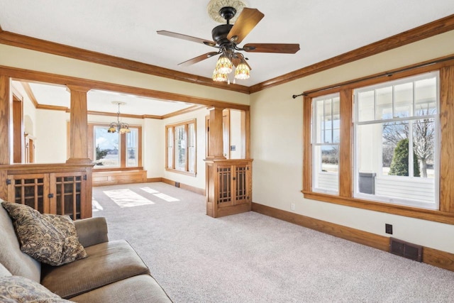 living area featuring decorative columns, visible vents, ornamental molding, and light colored carpet