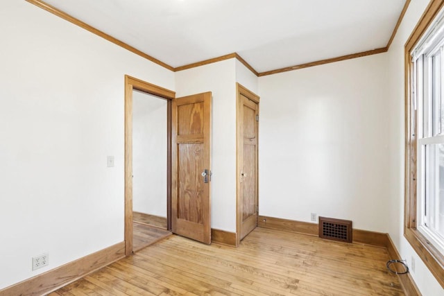 unfurnished bedroom featuring light wood finished floors, baseboards, visible vents, and ornamental molding