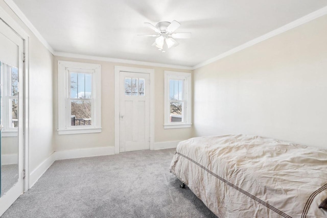 carpeted bedroom featuring ornamental molding, multiple windows, and baseboards