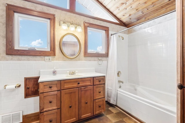 full bath featuring lofted ceiling, a wainscoted wall, visible vents, and tile walls