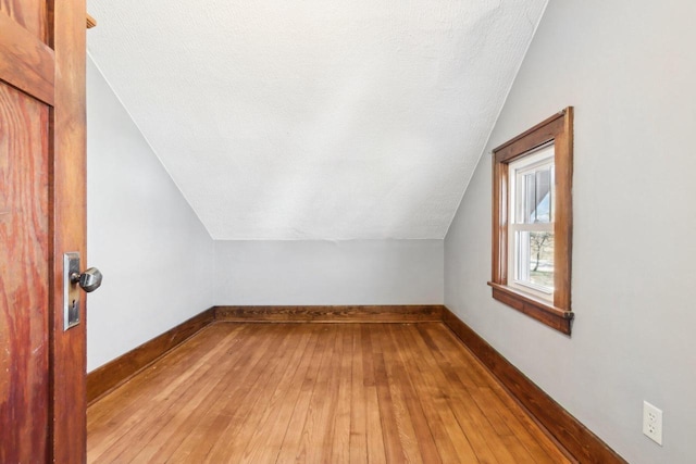 bonus room with lofted ceiling, a textured ceiling, baseboards, and wood finished floors