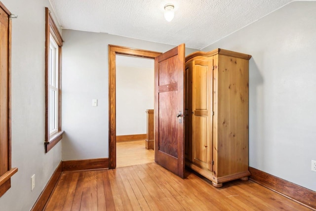 unfurnished bedroom with light wood-style flooring, baseboards, and a textured ceiling