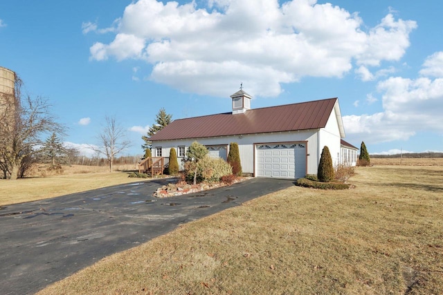 view of front of house with a garage, driveway, a front lawn, and metal roof