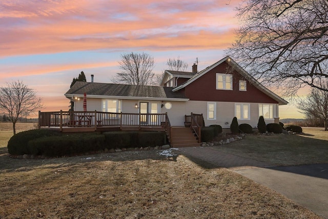 view of front facade featuring a chimney, a deck, and a front lawn