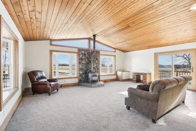 living area featuring lofted ceiling, wooden ceiling, light carpet, baseboards, and a wood stove