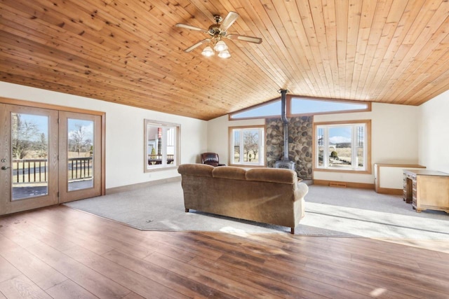 unfurnished living room featuring a wood stove, wooden ceiling, light wood-style flooring, and lofted ceiling