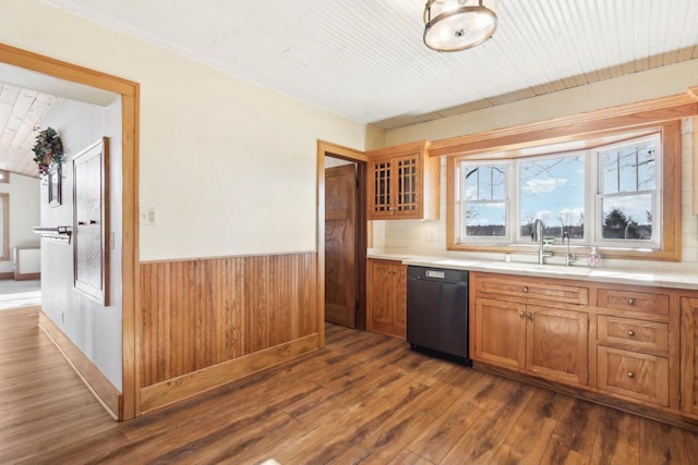 kitchen with glass insert cabinets, black dishwasher, light countertops, and brown cabinetry