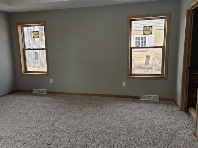 carpeted spare room featuring visible vents and baseboards