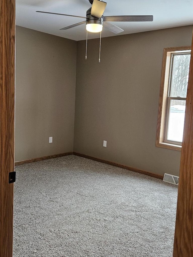 spare room featuring carpet, visible vents, ceiling fan, and baseboards