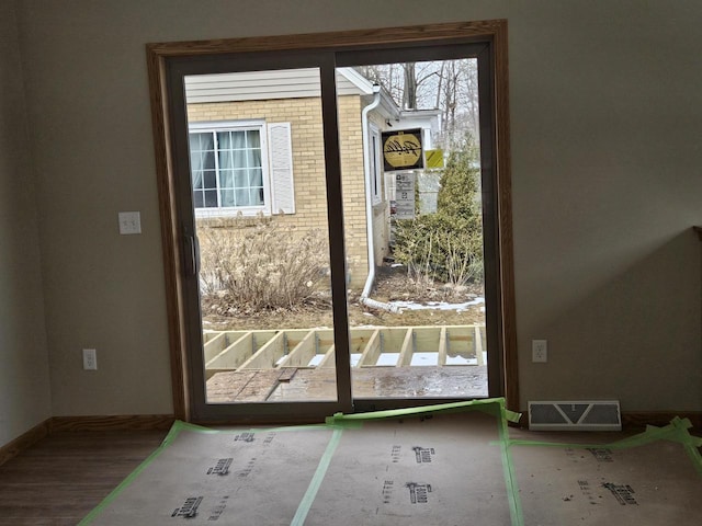 doorway with wood finished floors, visible vents, and baseboards