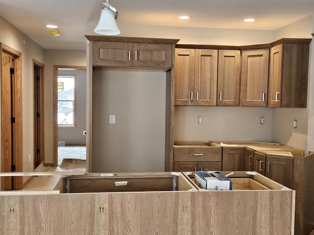 kitchen featuring recessed lighting, brown cabinets, and decorative light fixtures