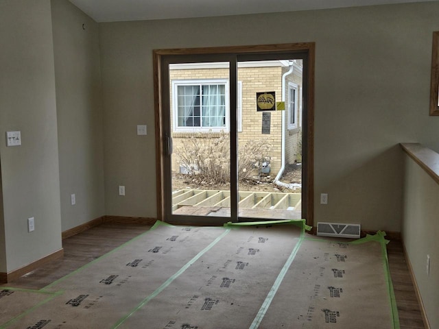 doorway featuring visible vents, baseboards, and wood finished floors