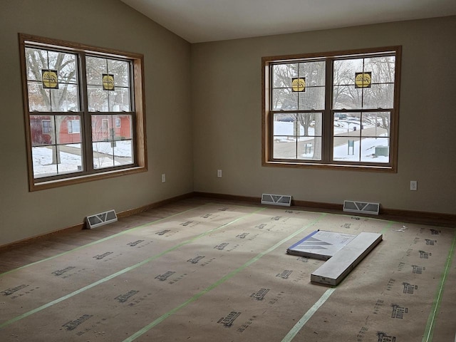 spare room with lofted ceiling, visible vents, and a healthy amount of sunlight