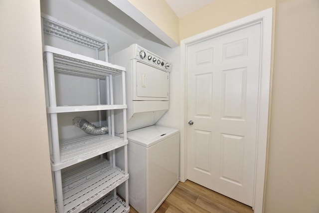 clothes washing area with stacked washing maching and dryer, laundry area, and light wood finished floors